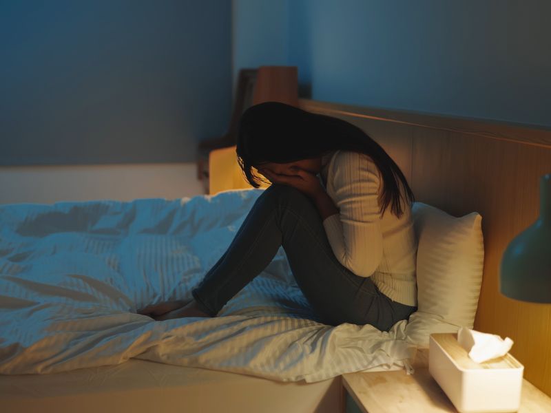 woman sitting on bed crying