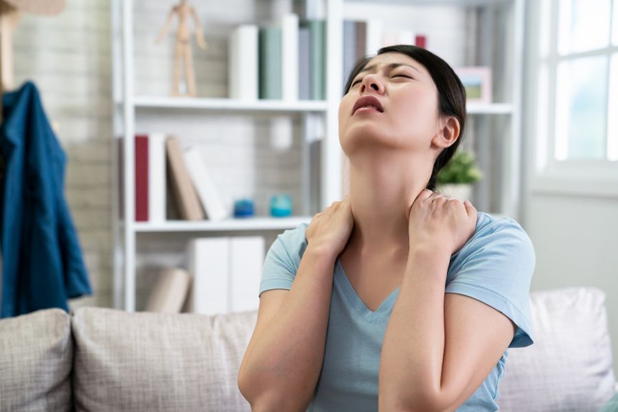 woman sitting with pain in her left shoulder